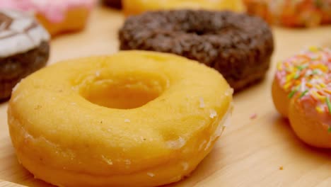 various flavors of donuts on a rotating wooden plate.