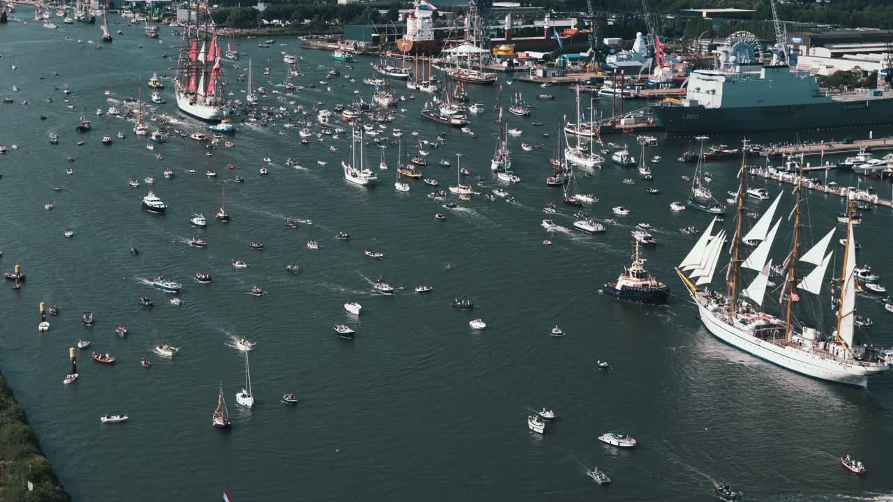 Aerial view circling left around tall ships surrounded by countless smaller boats