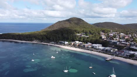 Aerial-view-of-an-Australian-coastline-with-parked-sailing-boats-and-a-mountain-next-to-a-coastal-town