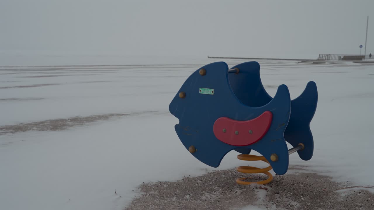 close-up of children's playground on snow-covered sandy beach in winter