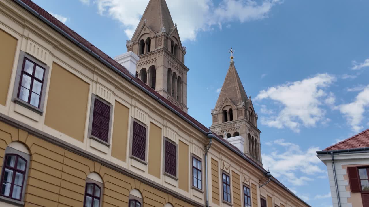 Elegant urban view of Pécs, showing the yellow landmark in the foreground with cathedral towers in the background