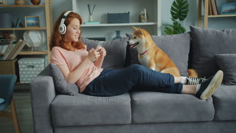teenage girl relaxing on couch with dog and listening to music