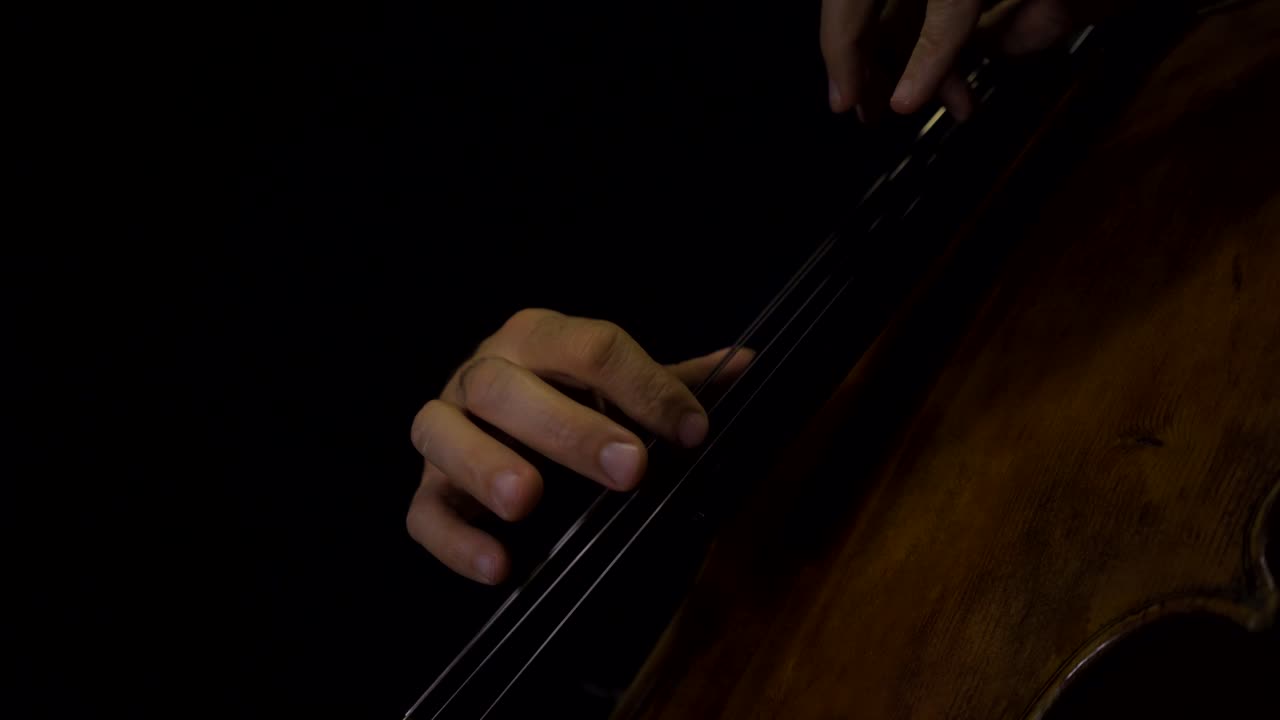 Close-up of cellist playing pizzicato notes without bow in hand.