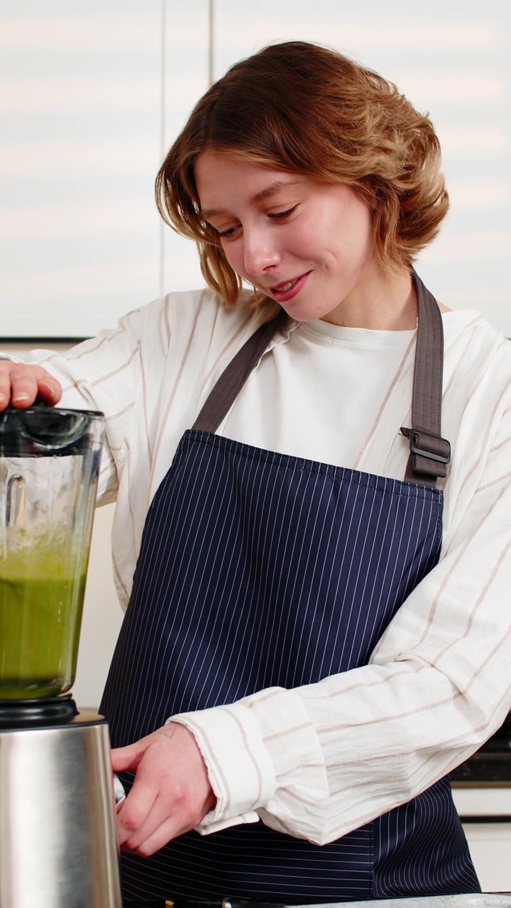 Giovane donna che prepara un frullato verde nel frullatore per una dieta sana e nutriente e la preparazione di alimenti in casa.