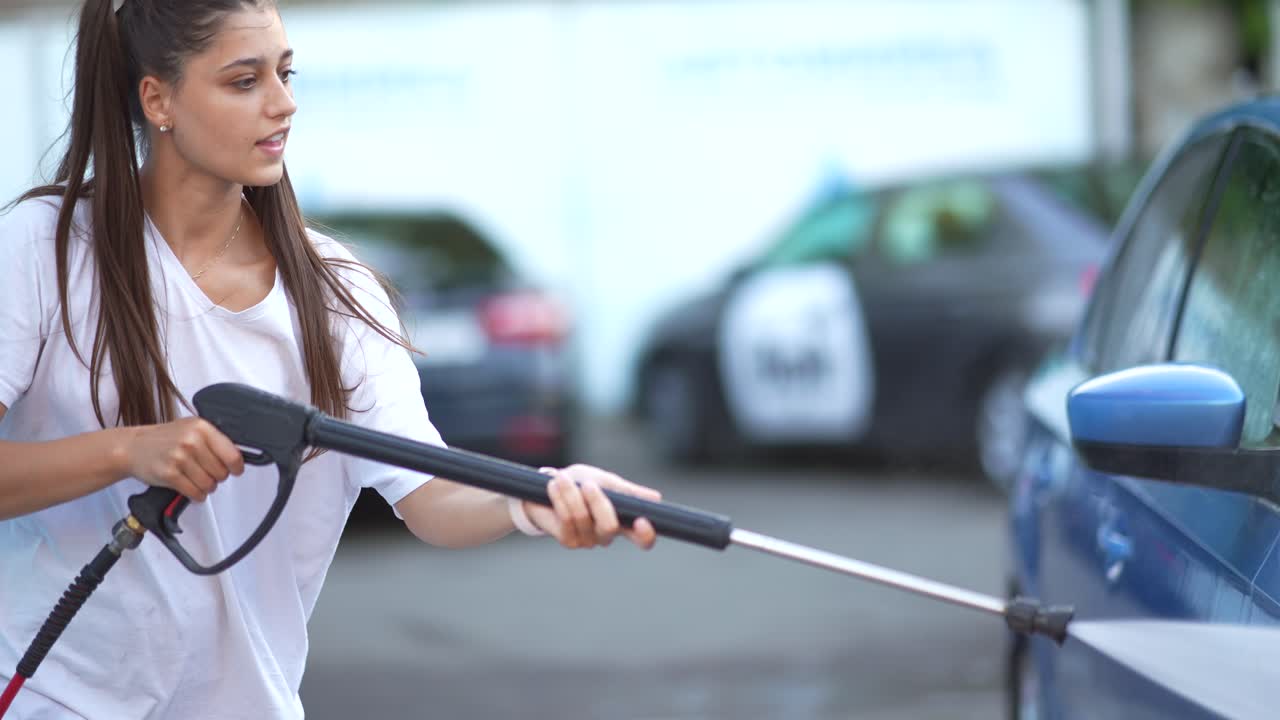 mujer lavando un coche con una lavadora a presión