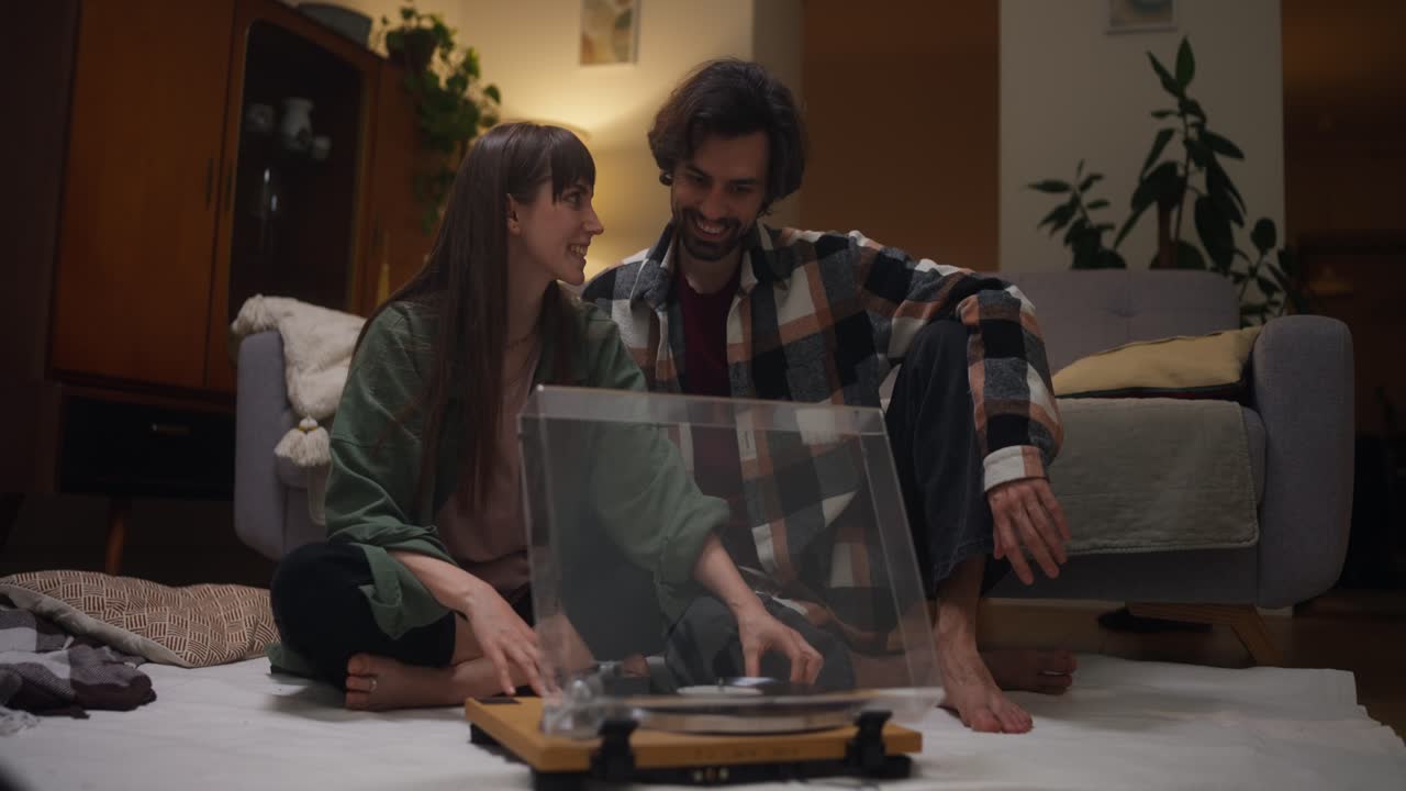 Couple listening to music on vinyl record player at home