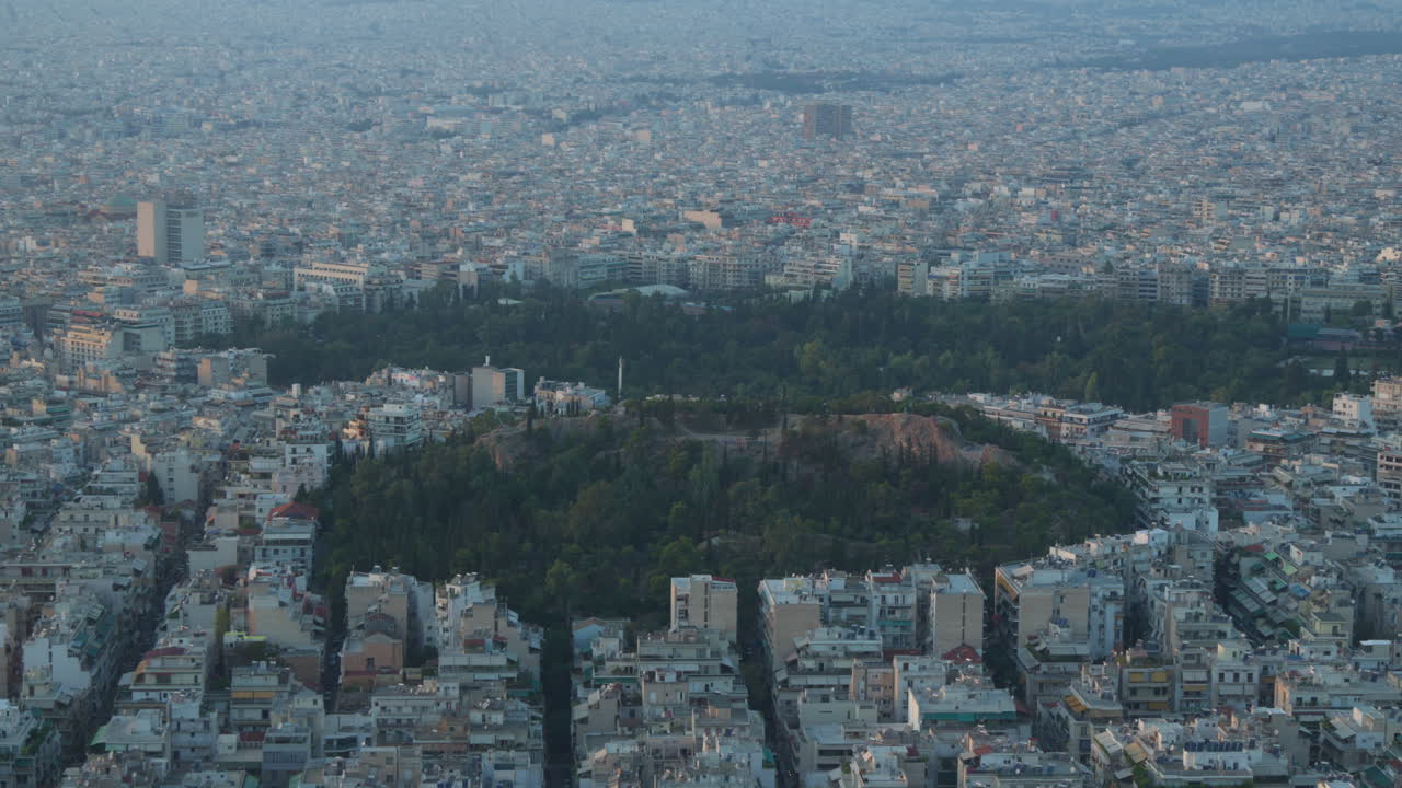 어두워지는 도시  ⁇ 창 가운데 울창한 언덕과 함께 아테네의 스카이라인