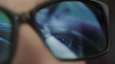 person driving a car reflected in sunglasses