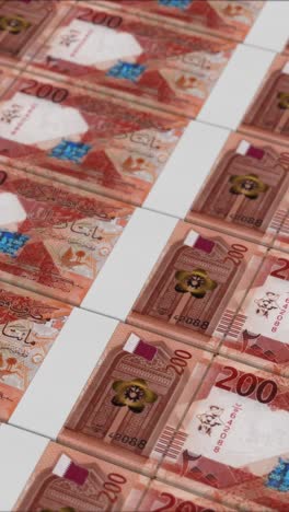 vertical video of 200 qatari riyal banknotes printed by a money press