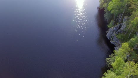 Beautiful-aerial-shot-of-a-steep-rocky-shoreline-of-forest-lake-in-the-borealis-wilderness