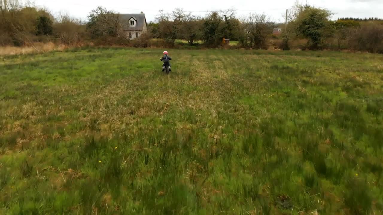 niño montando una bicicleta en el campo verde 4k