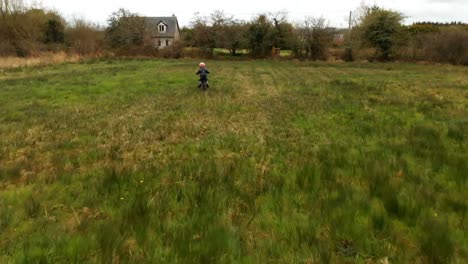 Boy-riding-a-bike-in-the-green-field-4k