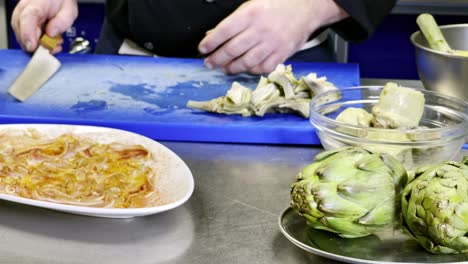 Cocinero-Limpia-El-Cuchillo-Después-De-Cortar-Corazones-De-Alcachofas