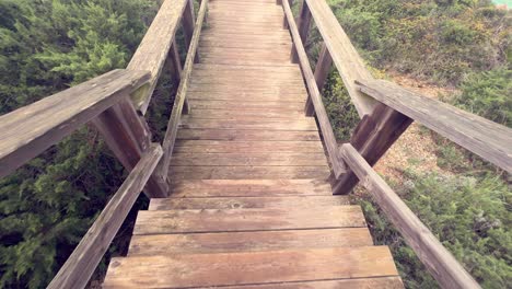 caminar por las escaleras de madera del paseo marítimo, revelando la superficie del agua del mar, la captura al aire libre durante el día, la recreación y el concepto de actividades de tiempo libre