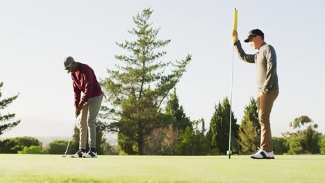 video of diverse male friends playing golf on golf field