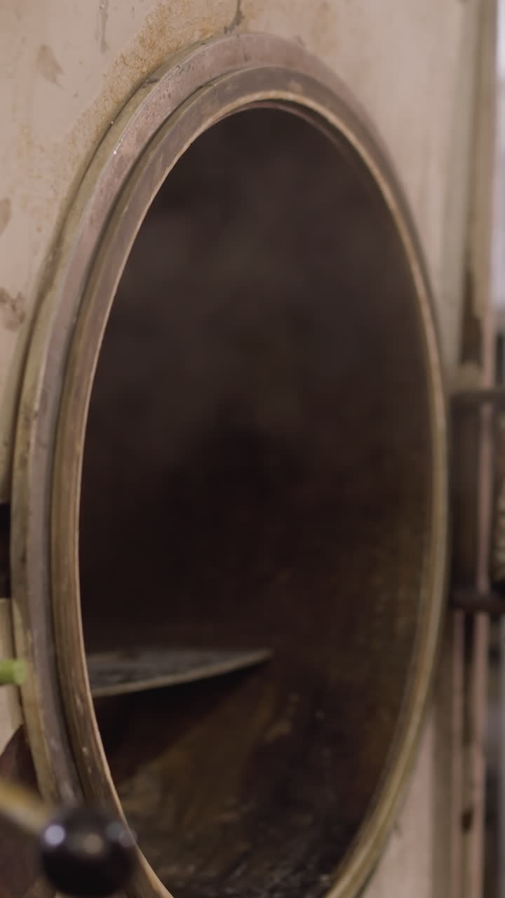 primer plano de la mano con guantes de un trabajador que opera una puerta de horno en un taller de cerámica