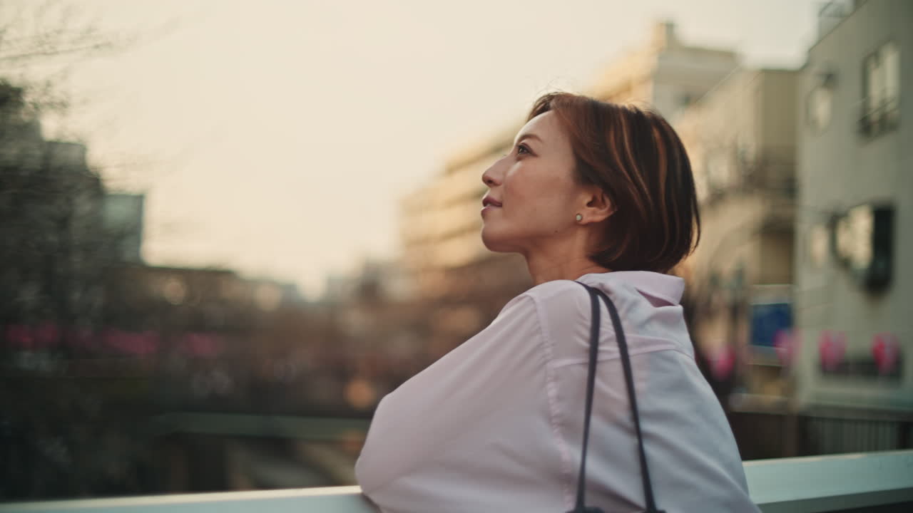 A woman looking out at the city from a bridge