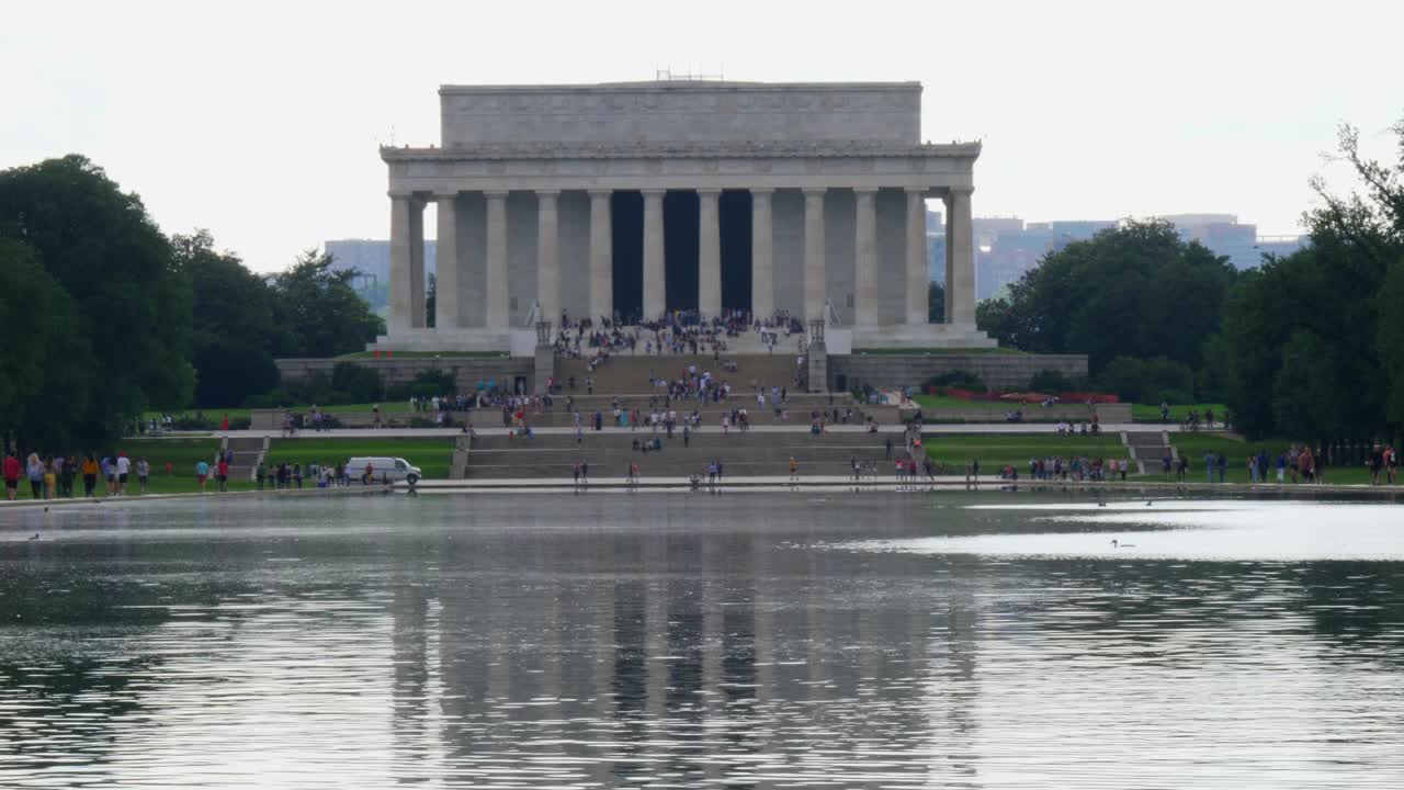 inclinación lenta hacia arriba desde el agua hasta los escalones delanteros del monumento a lincoln tomados del estanque de reflexión con personas en primer plano