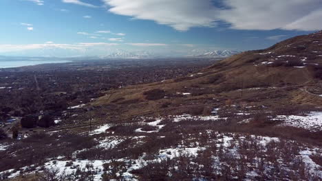 Flying-over-foothills-looking-at-an-urban-center-and-factory-in-the-valley-below