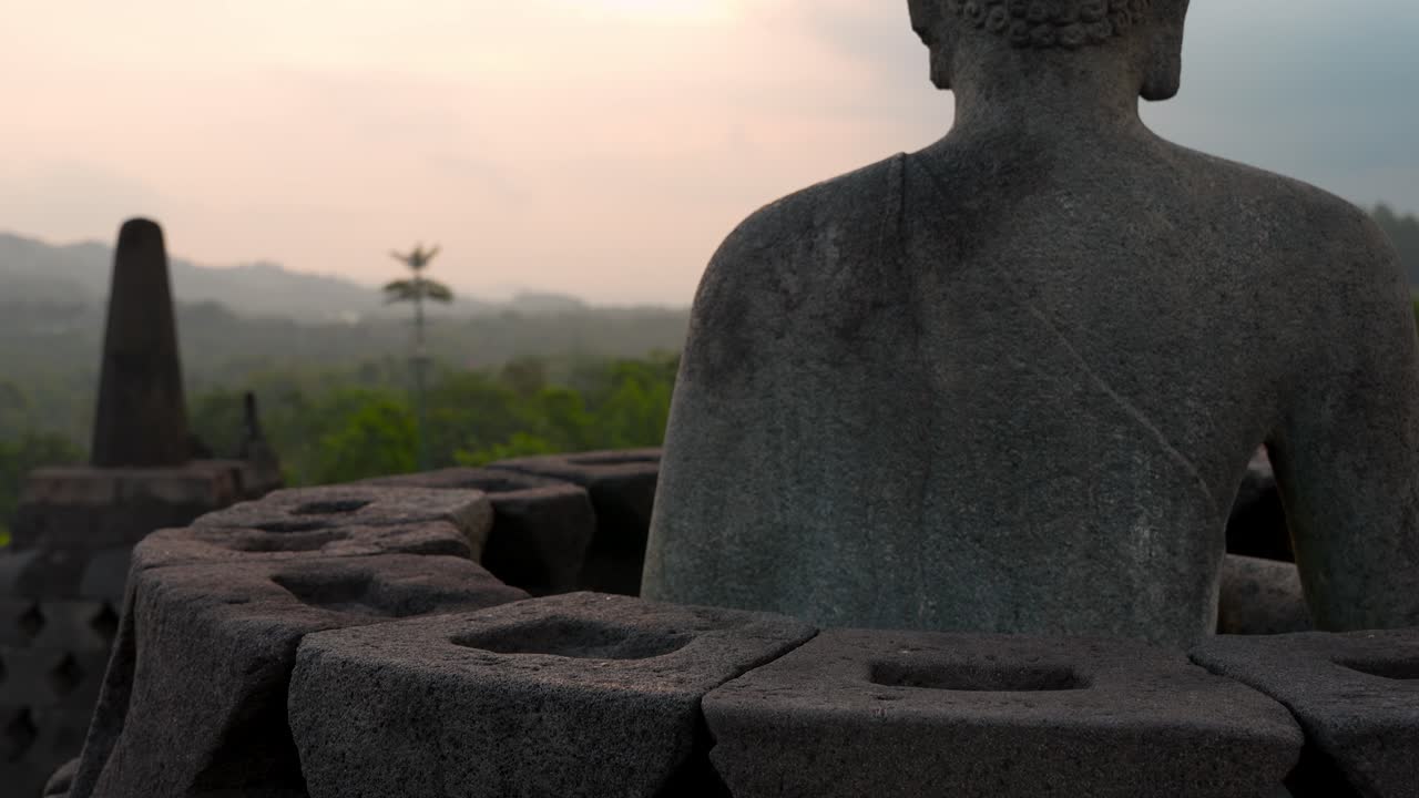 Primi piani del tempio di Borobudur, a Giava Centrale, in Indonesia, che mostrano stupa e statue di Buddha in silhouette al tramonto, sullo sfondo di paesaggi tropicali e cieli serali caldi