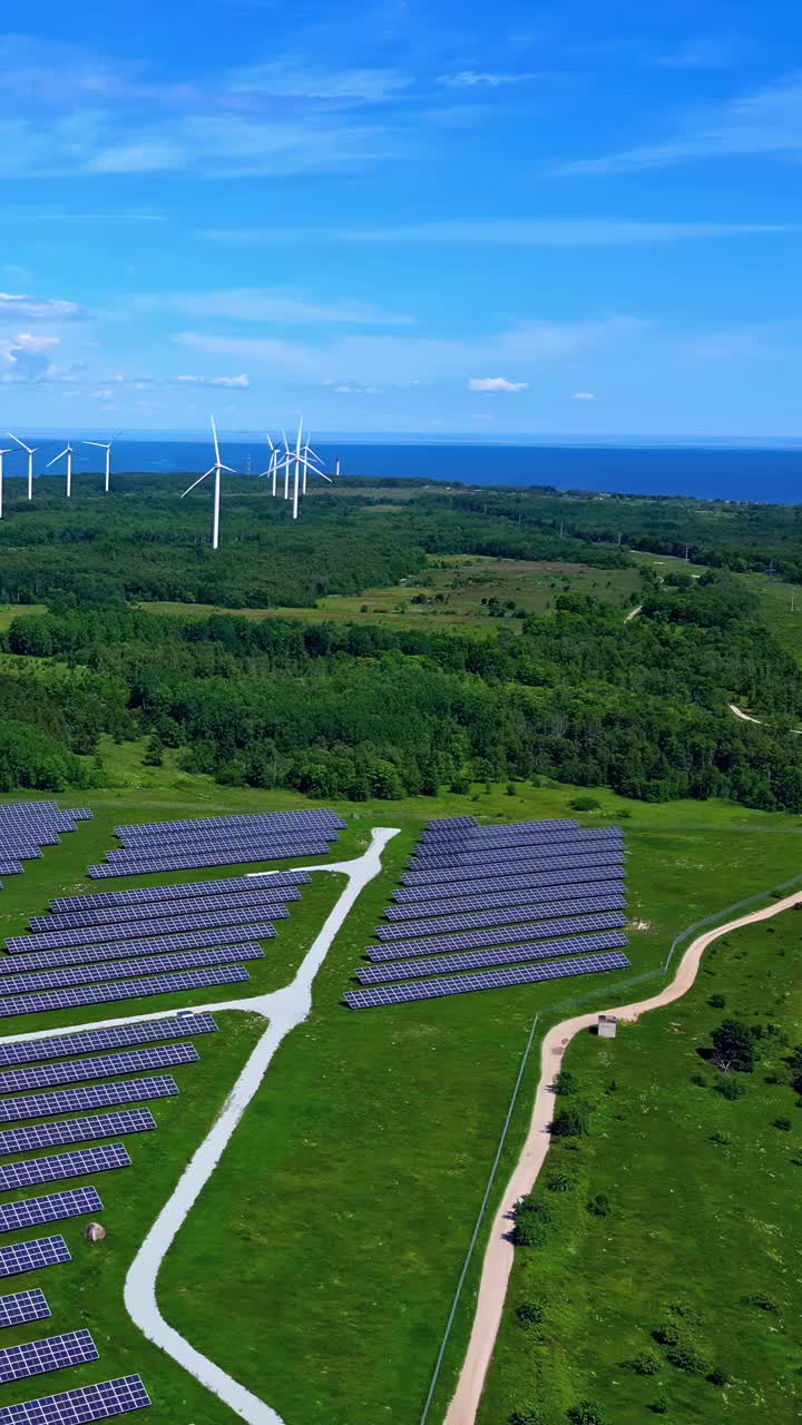Aerial view of a Latvian landscape showcasing large solar panel arrays and wind turbines with the Baltic Sea in the backdrop, symbolizing sustainable energy
