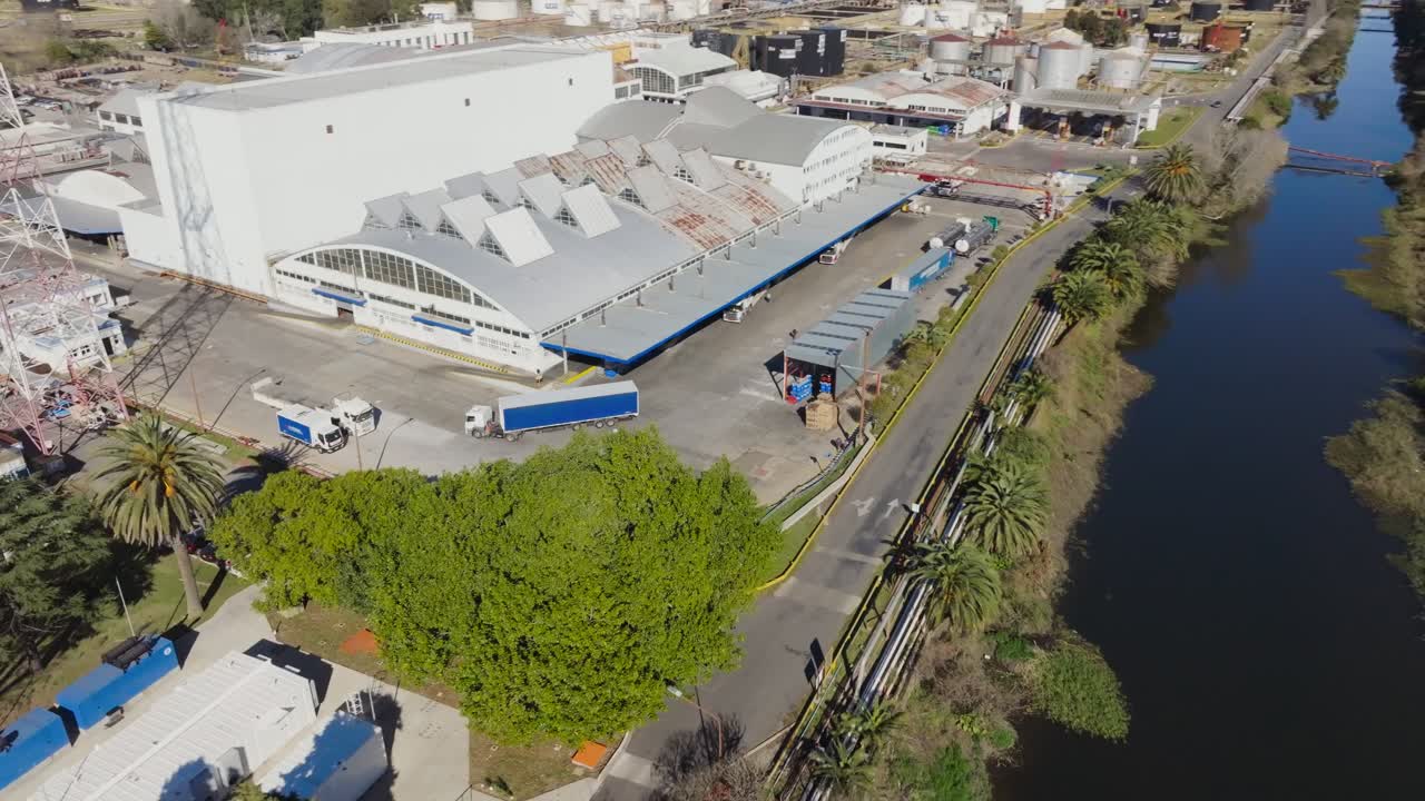 Aerial drone footage showing an oil and gas refinery storage tanks and industrial structures framed by suburban neighborhoods nearby