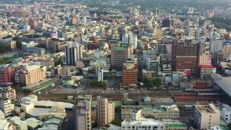 Aerial-drone-flyover-main-railway-station-capturing-the-railroad-tracks-and-sunset-downtown-cityscape-of-Douliu-city,-Yunlin-county,-the-countryside-of-Taiwan