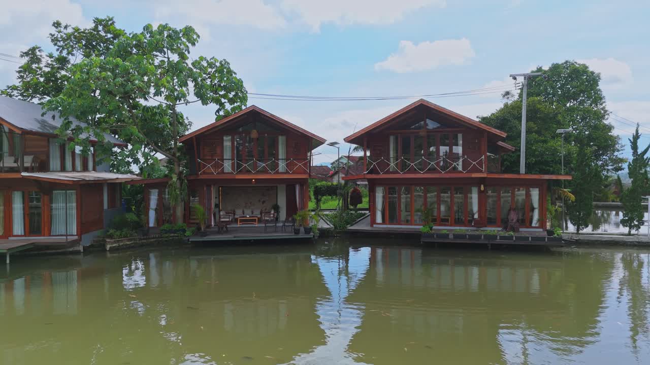 Những biệt thự gỗ hiện đại được xây dựng trên hồ nước yên ả dưới bầu trời xanh.