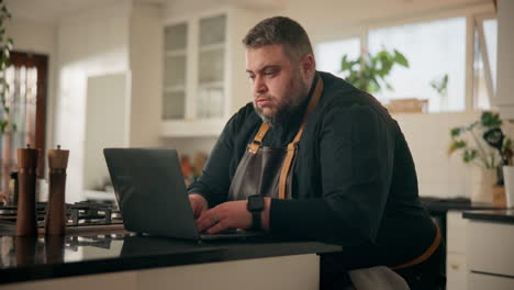 man working on laptop in kitchen