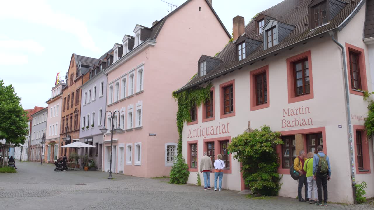 Charming street view of pastel historic buildings in Saarbrücken, Germany with people walking.