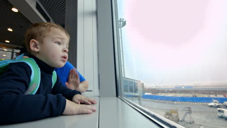 mother and little son looking out the window at airport