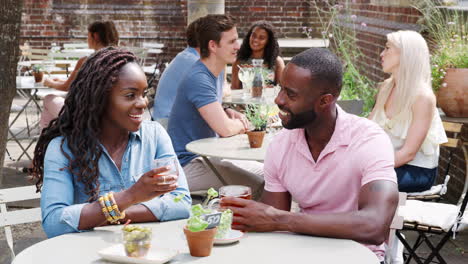 young couple meeting for drinks at outdoor tables in restaurant