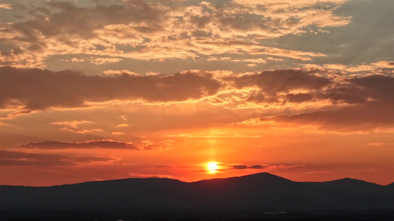 Un timelapse in 4K realizzato con drone del sole che tramonta dietro una catena montuosa del Sud-Ovest, caratterizzato da una distorsione ondulata surreale causata dall'atmosfera densa e dalla foschia di fumo degli incendi boschivi