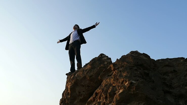 Businessman standing on top of a mountain