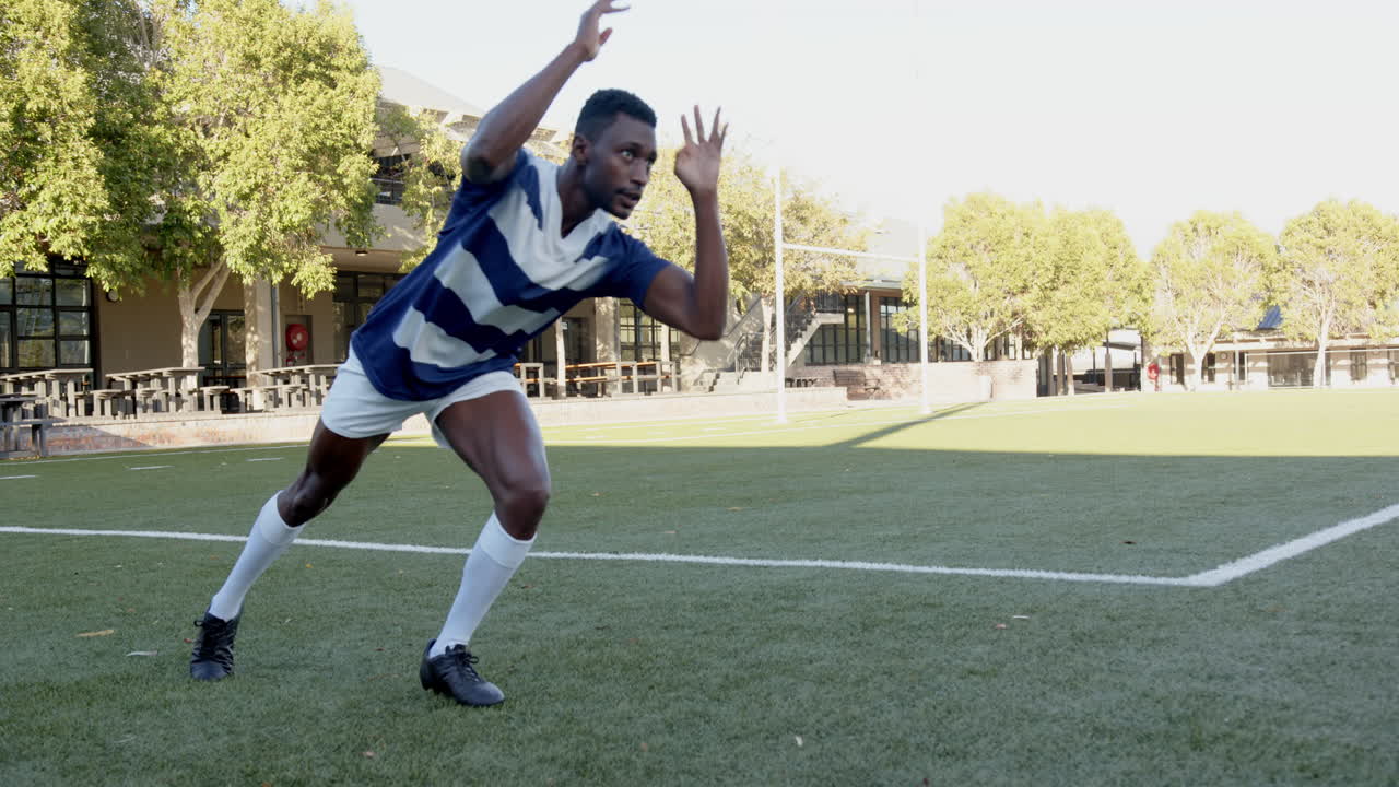 Playing rugby, african american man in sports catching ball on field, focusing on game, copy space