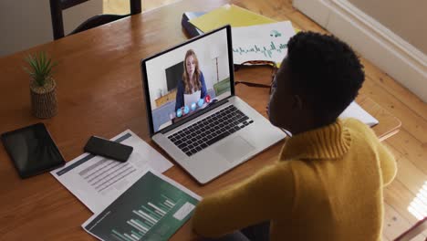 mujer afroamericana que usa una computadora portátil en una videollamada con una colega que trabaja desde casa