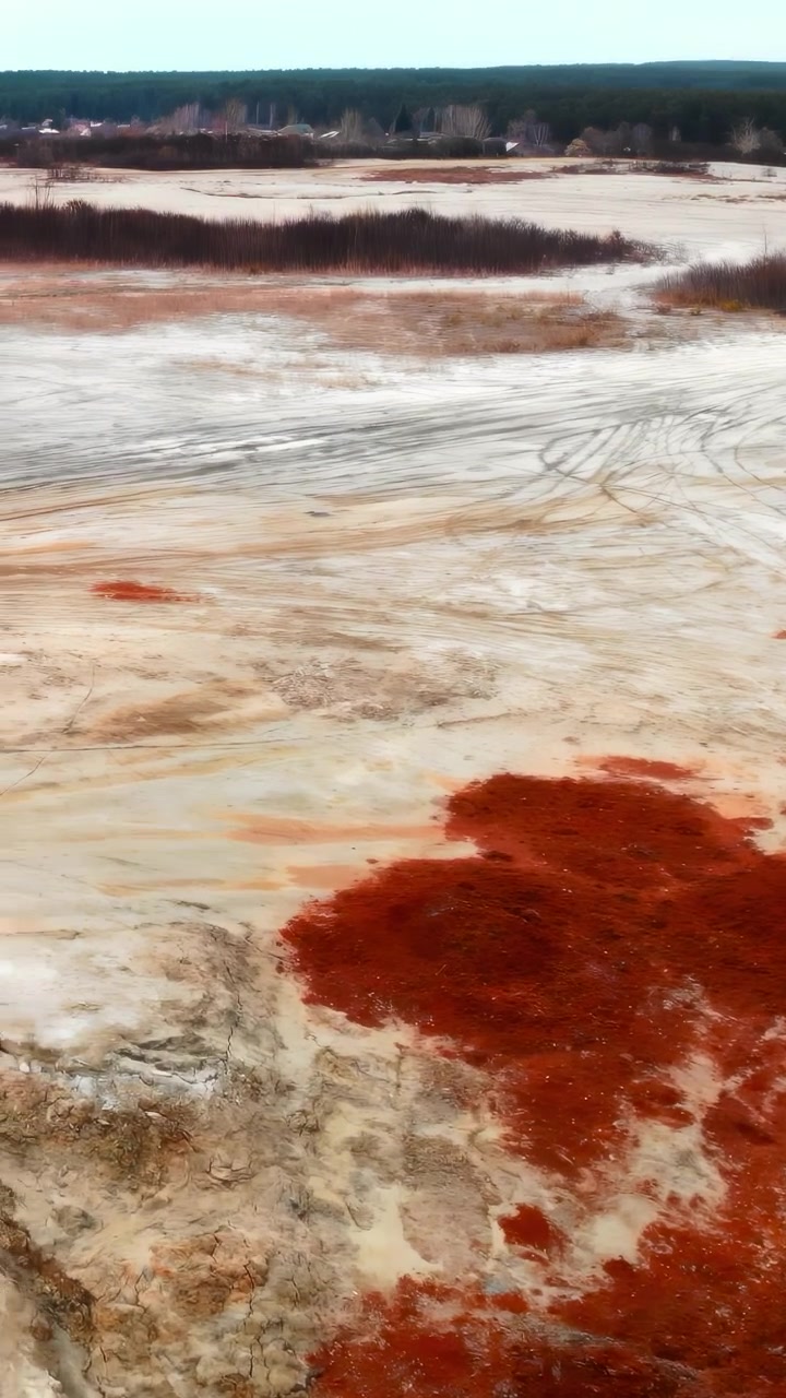 Terre ocre et rouillée sur une plaine minière aride, panorama aérien révélant des dépôts salins et des zones oxydées, asséchée.