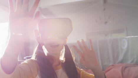 happy asian girl at home, sitting on floor in living room enjoying using vr headset, backlit