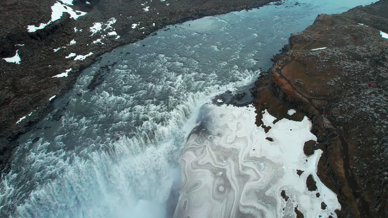 Aerial view of Dettifoss waterfall, showcasing its powerful flow amidst a snow covered landscape in Iceland