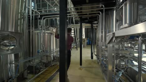 young brewer wearing a leather apron carries a barrel of craft beer at a modern brewery