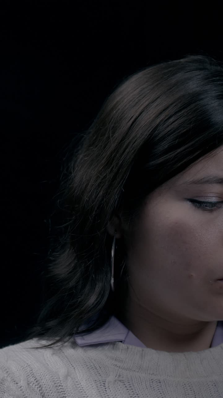 Close-up vertical video showcasing a focused woman using her smartphone in low light. Ideal for mobile content, social media stories, and vertical platforms. Captivating, intimate shot