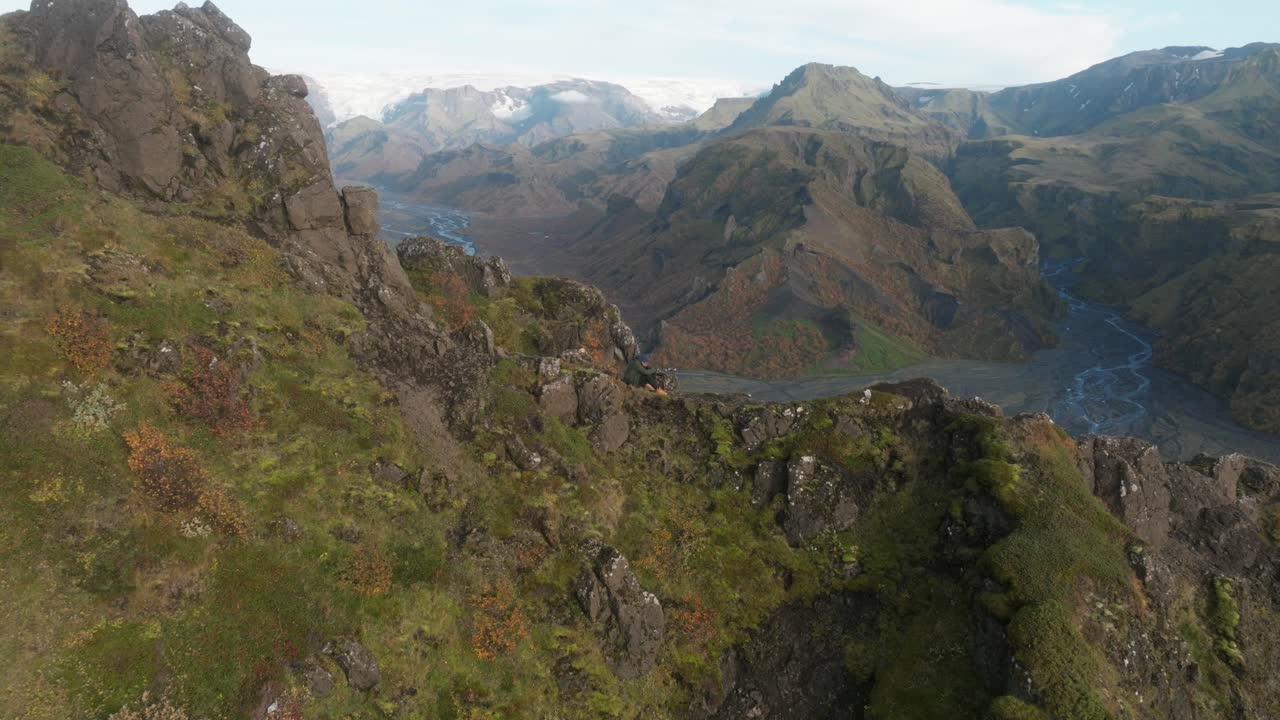 절벽 가장자리에 있는 사진가가 아이슬란드 계곡의 이미지를 촬영하고 있습니다.