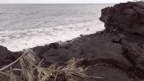 Waves-on-a-volcanic-rock-beach,-gloomy-day