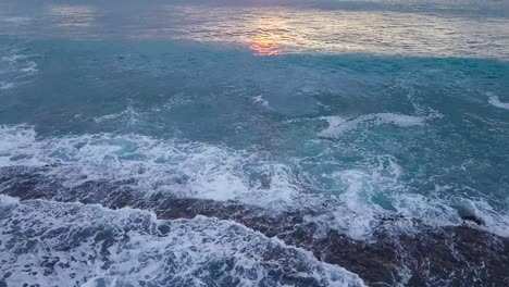 Puesta-De-Sol-En-El-Océano-Pacífico-En-La-Costa-Oeste-De-Oahu-Honolulu-Hawaii-Durante-La-Hora-Dorada-Con-Tonos-Brillantes-De-Amarillo-Anaranjado-Y-Azul-Sobre-Olas-Y-Espuma-De-Mar,-Revelación-De-Inclinación-Aérea