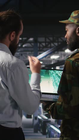vertical video army operators in data center using laptop to run drone control software