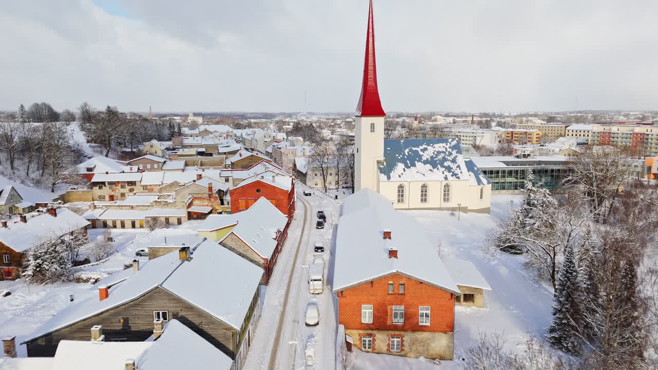 Aerial view backwards over snowy streets at the Rakvere church, winter in Estonia
