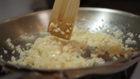 saltear cebollas picadas en una sartén caliente usando una espátula de madera - cámara lenta