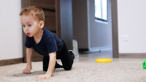 active toddler boy crawling by the carpet. smiling cute kid playing a game at home.