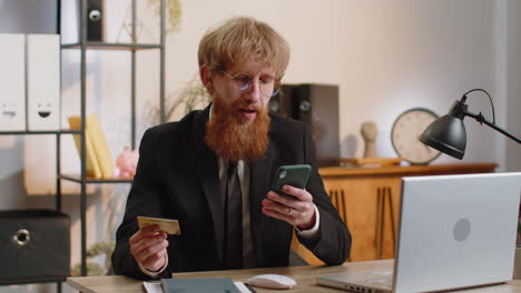 business man making online purchase payment shopping with credit bank card and smartphone at office