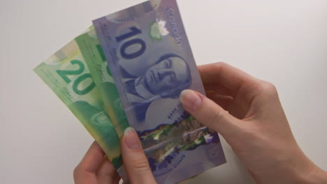 Las-Manos-De-Una-Mujer-Caucásica-Contando-$50-En-Dinero-Canadiense-Y-Colocando-Los-Billetes-Sobre-La-Mesa